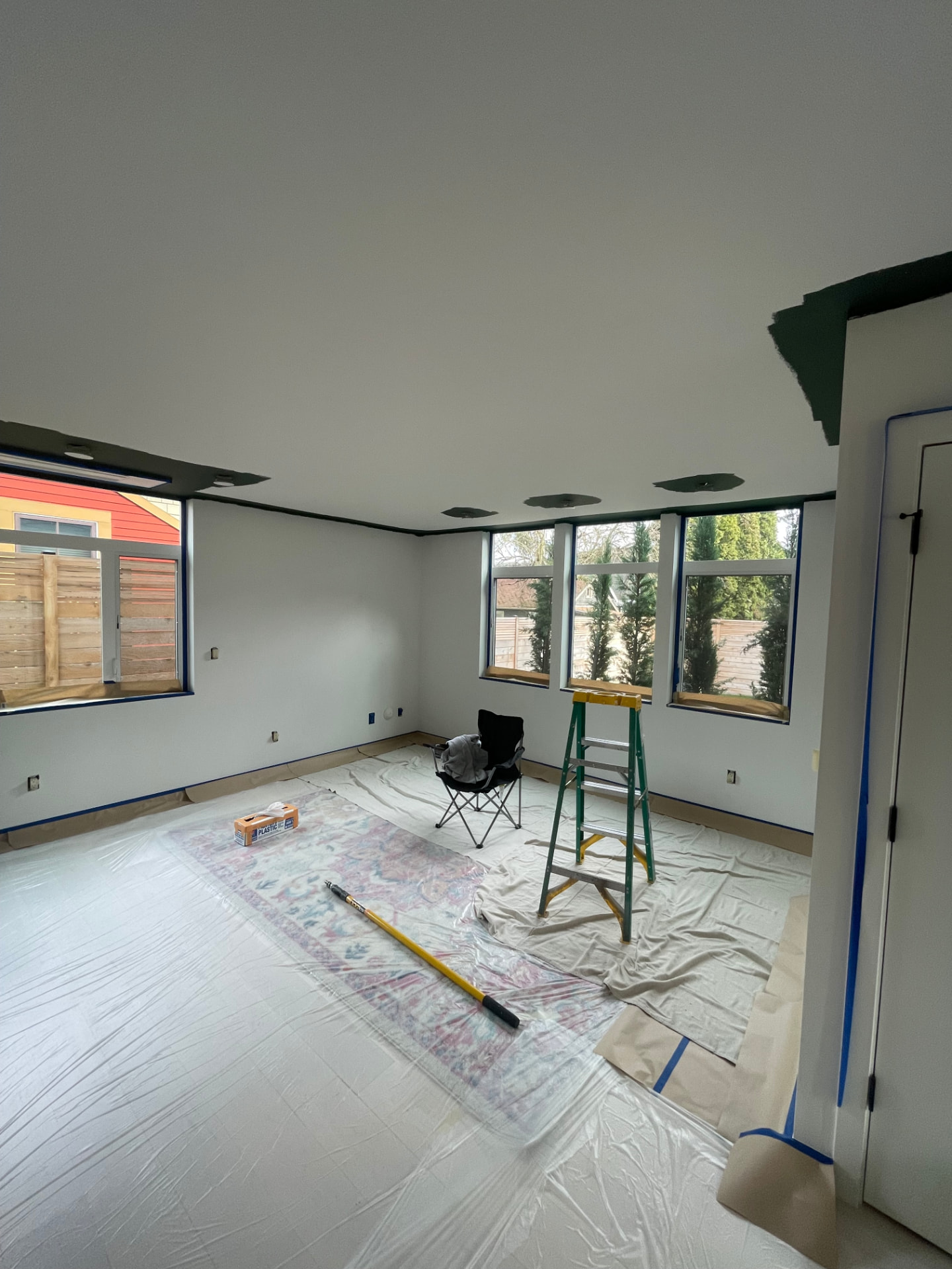 Interior living room mid-prep with white walls and plastic floor coverings.