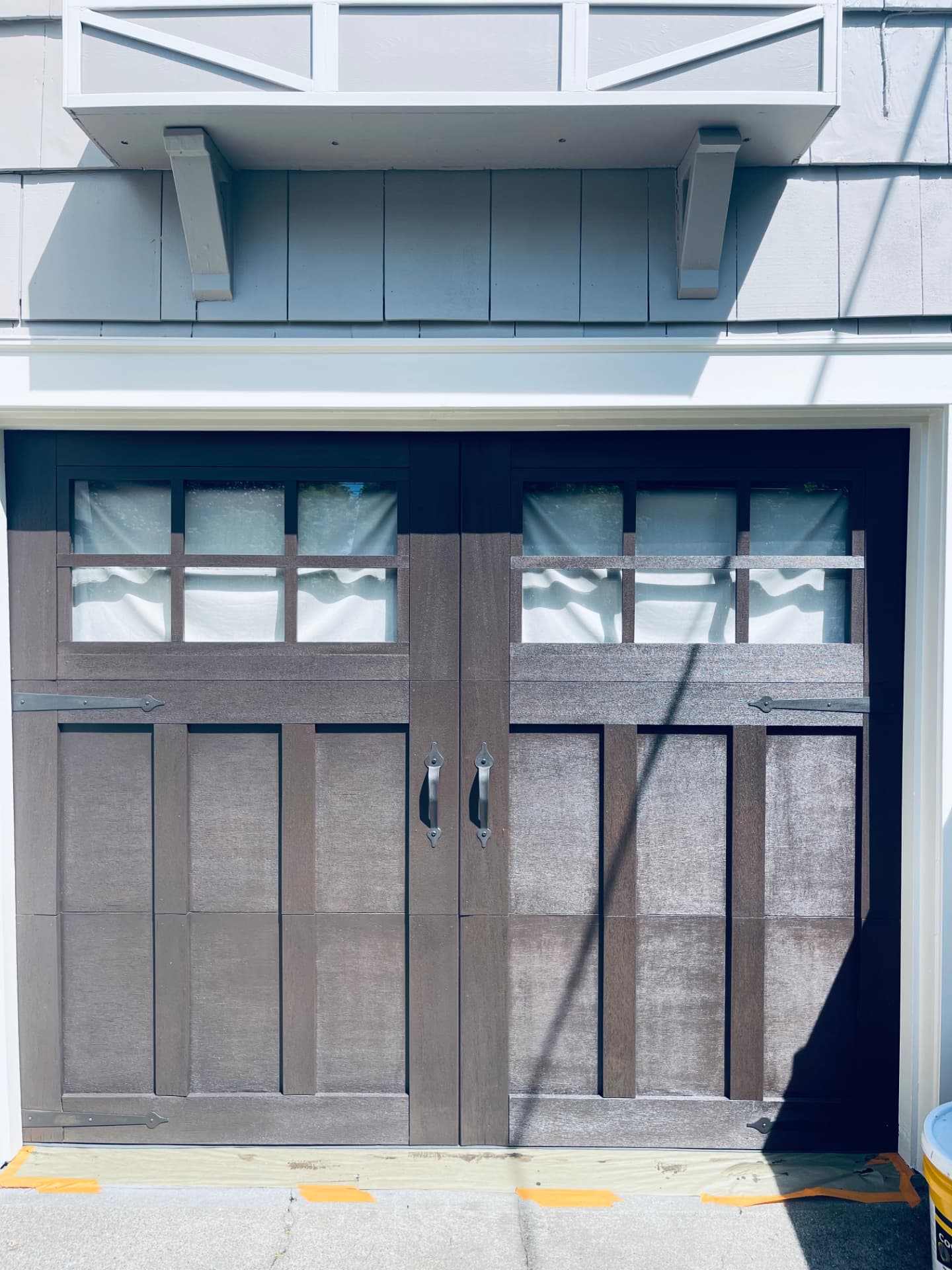 Finished dark brown wooden garage door with small windows.